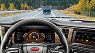 Peterbilt Model 579 Diesel On-Highway Interior Driver POV of Steering Wheel and Gauges Featuring Lane Keep Assist on Mountainous Treelined Highway - Thumbnail